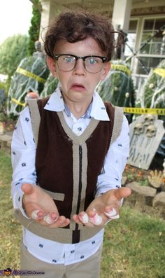 a young boy wearing glasses and holding his hands out in front of him with both hands