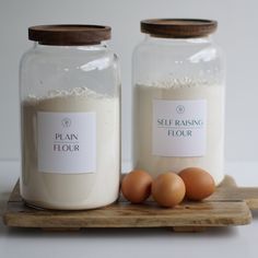 two glass jars with flour and eggs on a wooden tray next to each other, both labeled plan flour