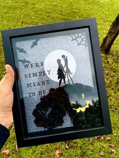 a person holding up a framed paper cutout with the words we're simply meant to be