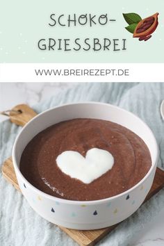 a bowl filled with chocolate pudding on top of a wooden cutting board next to a spoon