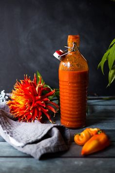 a bottle of hot sauce next to some peppers on a napkin and potted plant