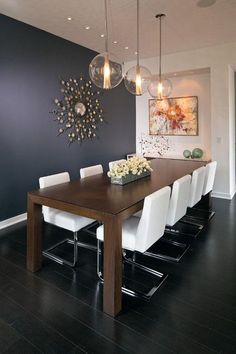 a dining room table with white chairs and chandelier hanging from it's ceiling