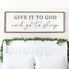 a bed with pillows and a sign above it that says give it to god and go to sleep