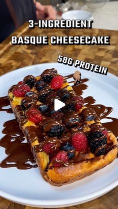 a piece of bread with chocolate sauce and berries on top is sitting on a white plate