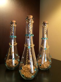 three glass vases filled with sand and candles on a table next to a wall