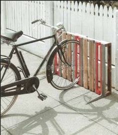 a bike parked next to a wooden fence on the side of a street with red bars