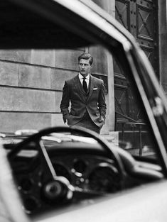 a man in a suit and tie standing next to a car