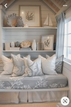 a couch with many pillows and pictures on the wall above it, along with bookshelves