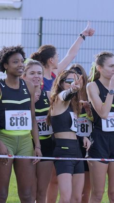 a group of young women standing next to each other on top of a race track