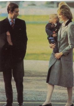 a man in a suit and tie standing next to a woman with a baby on her lap