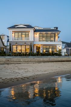 a large white house sitting on top of a sandy beach next to the ocean at night