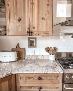 a kitchen with wooden cabinets and white marble counter tops, an oven and toaster