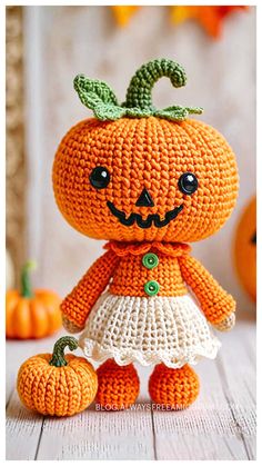 an orange crocheted pumpkin doll sitting on top of a white table next to some pumpkins