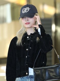 a woman wearing a hat and carrying a black bag