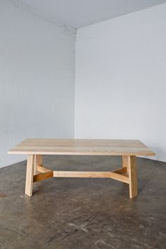 a wooden table sitting on top of a cement floor next to a white brick wall