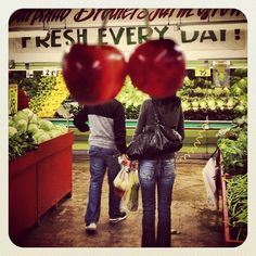 two people are walking in front of a produce stand with apples on display and the words fresh every day above them