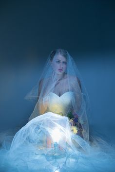 a woman in a wedding dress sitting on the floor with her hands under her face