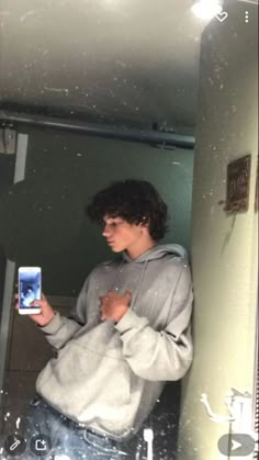 a man standing in front of a mirror holding a cell phone