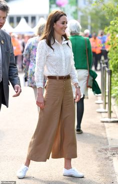 a woman walking down a sidewalk next to a man in a suit and white shirt