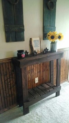 a wooden table with two vases on top of it in front of a wall