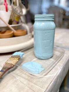 a blue mason jar sitting on top of a table next to a brush and paintbrush