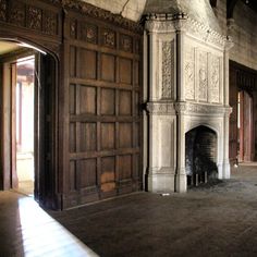 an old fireplace in the middle of a room with wooden paneling on the walls