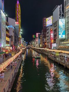 a river running through a city with tall buildings on both sides and people sitting at tables near the water