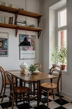 a dining room table and chairs in front of a window with bookshelves on the wall