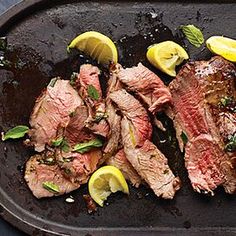 steak with lemons and mint garnish on a grilling pan, ready to be cooked