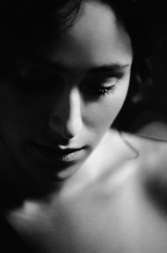 a black and white photo of a woman's face with her hand on her shoulder