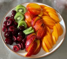 a plate full of sliced fruit including apples, cherries and kiwis