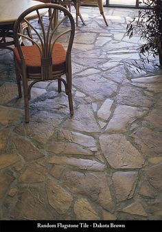 a table and chairs sitting on top of a stone floor next to a large window