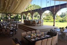 an outdoor dining area with tables and chairs set up for a formal function in the shade