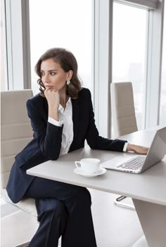 a woman sitting at a desk with a laptop and coffee cup in front of her