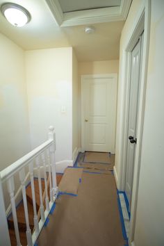 an empty hallway with blue tape on the floor and white door in the corner,