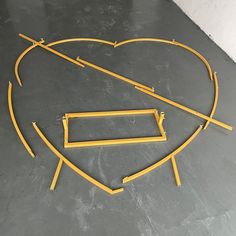 a heart shaped object on the ground with some yellow sticks sticking out of it's sides