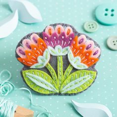 a close up of a flower on a table with buttons and yarn next to it