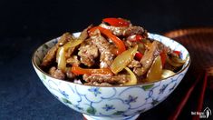 a close up of a bowl of food with chopsticks in the back ground