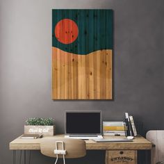 a desk with a laptop computer on top of it next to a wall mounted painting