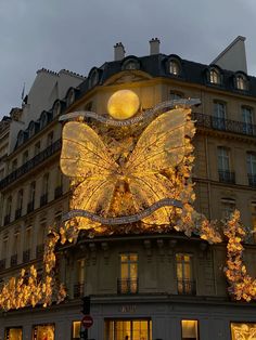 a building with christmas lights on it and a giant butterfly in the middle of the street