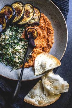 a white plate topped with different types of food next to two slices of bread and an eggplant