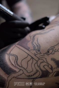 a close up of a person with tattoos on their arm holding a cell phone in his hand