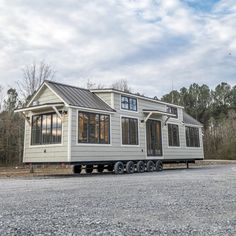 a tiny house sitting on the back of a flatbed trailer in a gravel lot