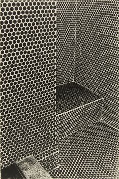 an old black and white photo of a shower with metal grates on the walls