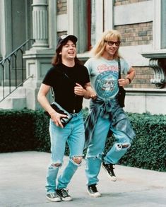 two people walking down the street with one person wearing ripped jeans and black t - shirt