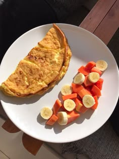 an omelet and sliced up fruit on a white plate