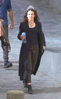 a woman wearing a tiara walking down the street with a water bottle in her hand