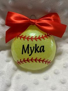 a personalized softball ornament with a red bow on it's head