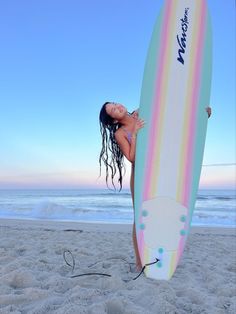 a woman is standing on the beach with her surfboard in front of her face