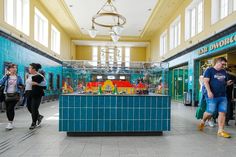 people are walking through an indoor mall with brightly colored tiles on the walls and floor